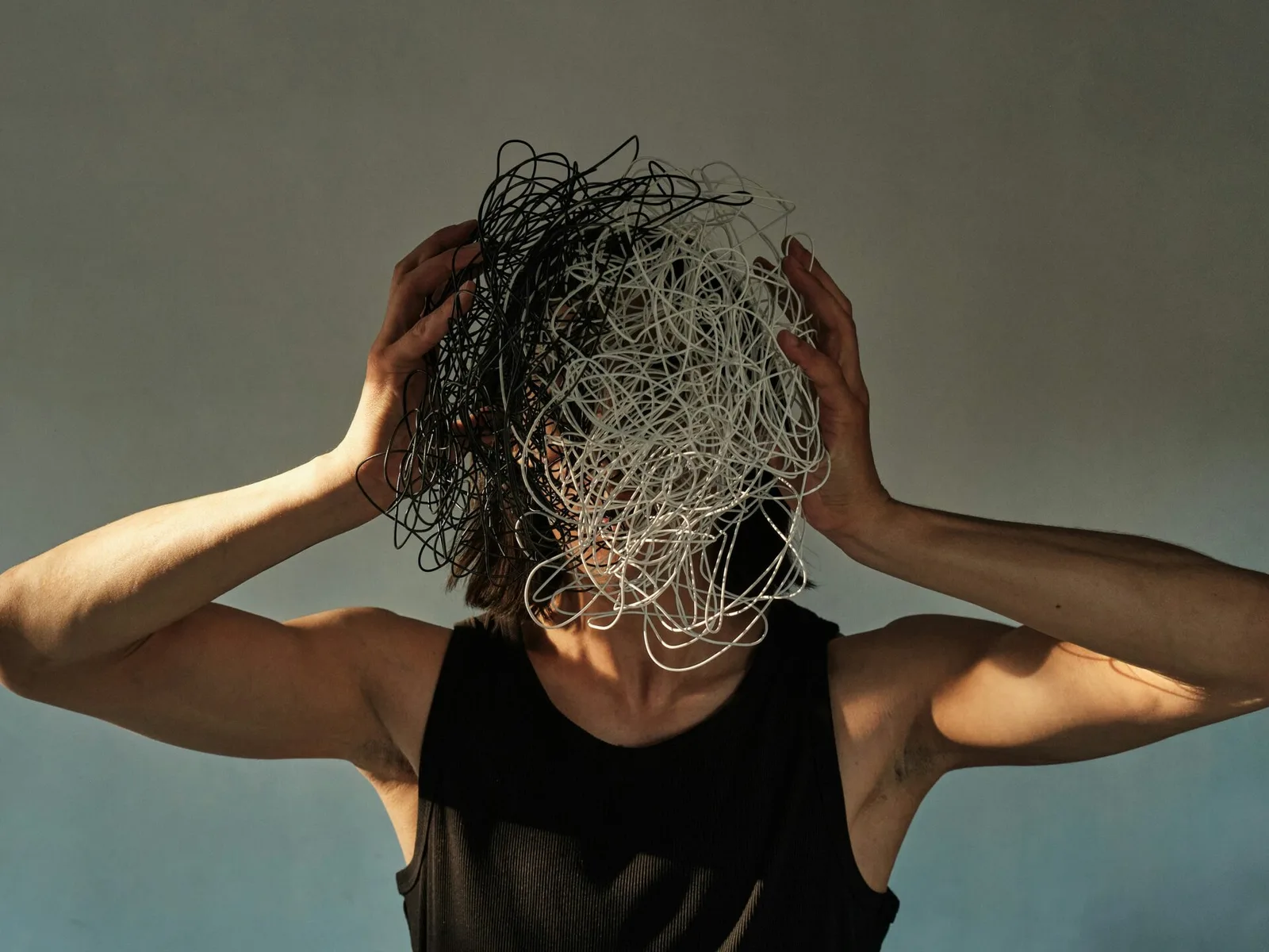 A person with their head wrapped in a tangle of white and black wires, representing broken, tangled links